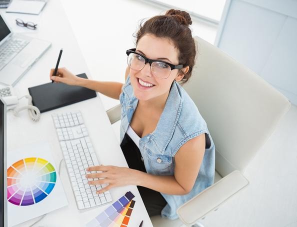Professional graphic designer at workstation with color swatches and drawing tablet