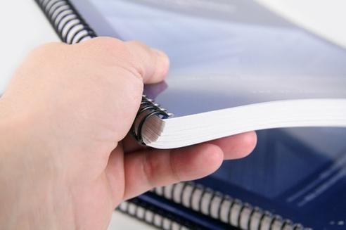 Hands holding a spiral-bound technical manual
